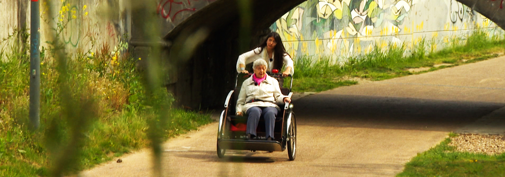 Trivelo fiets met een oudere dame op de zetel vooraan op de fiets